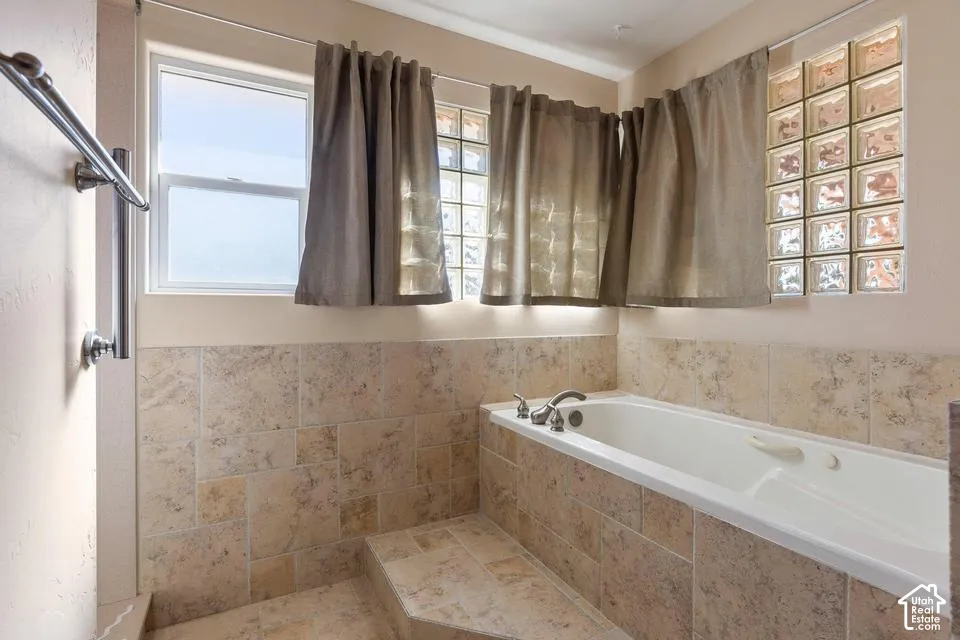 Built-in soaking tub with chrome fixtures, surrounded by neutral-toned tile