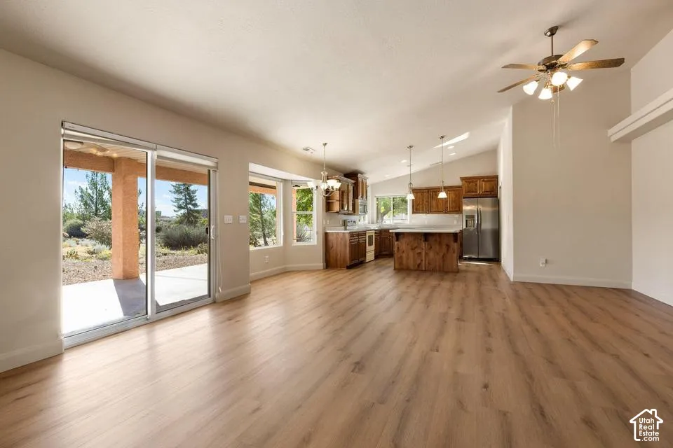 Open-concept living space featuring wood-finish flooring, vaulted ceilings, and a kitchen with wood cabinetry