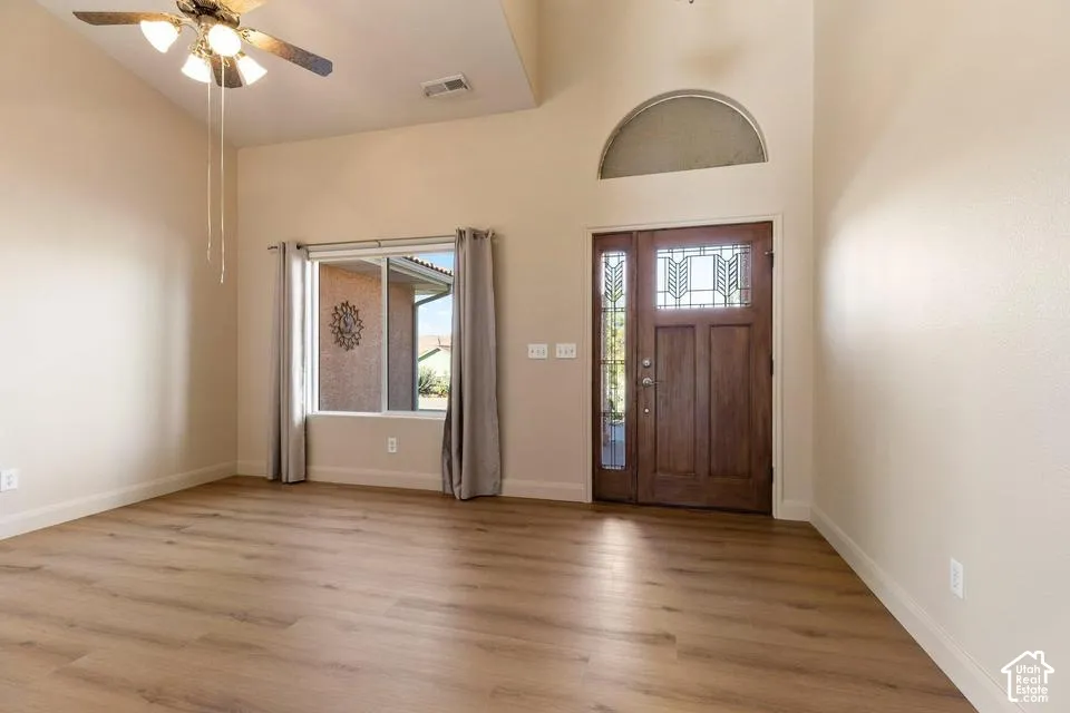 Wood-finish flooring with a vaulted ceiling, ceiling fan, and large window
