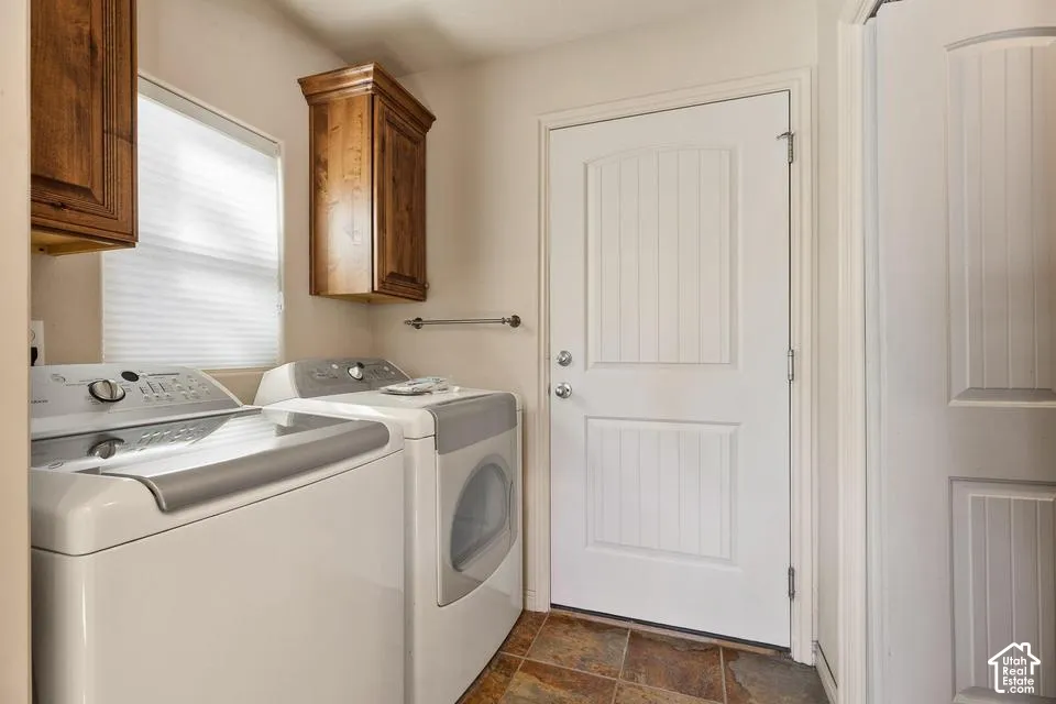 Laundry area featuring wood-finish cabinetry, a white paneled door, and tiled flooring