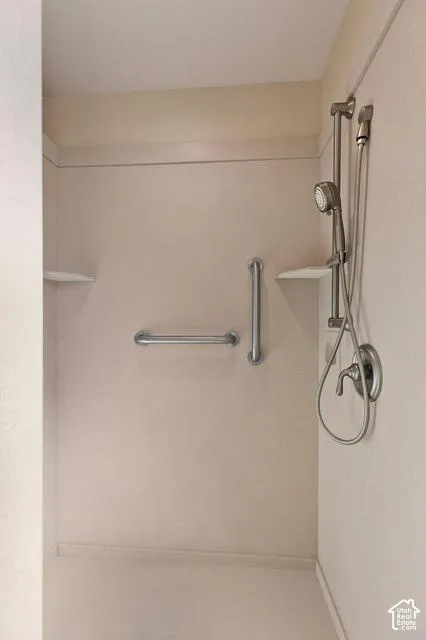 Walk-in shower with integrated corner shelving, brushed nickel fixtures, and safety grab bars