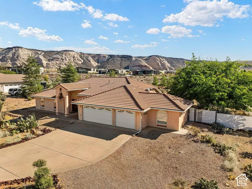 Terracotta tile roof with a prominent portico entry, two-car garage, and desert landscaping
