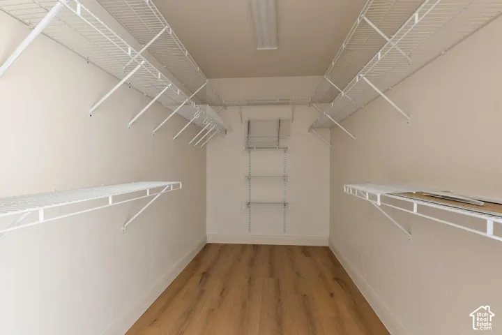Walk-in closet featuring wood-finish flooring, white wire shelving, and overhead lighting