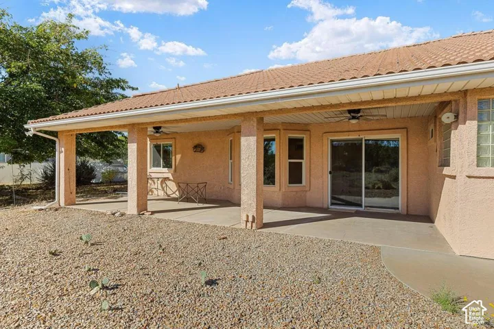 Expansive covered patio with concrete flooring, stucco pillars, and an overhead ceiling fan