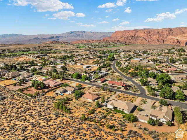 Residential development with winding streets and established landscaping, set against a backdrop of distant mountains