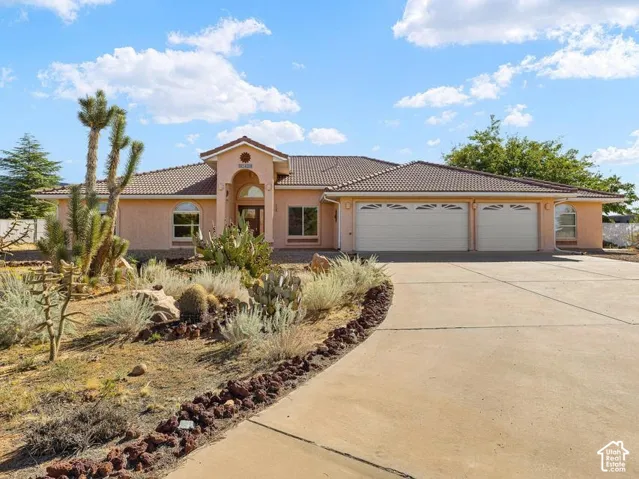 Southwestern-style residence featuring a terracotta stucco exterior, metal-trimmed architectural detailing, and a three-car garage with bronze-finish doors