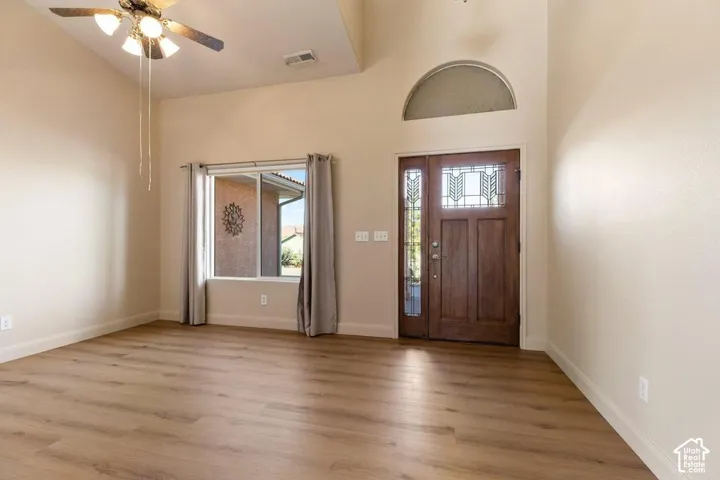 Wood-finish flooring with a vaulted ceiling, ceiling fan, and large window