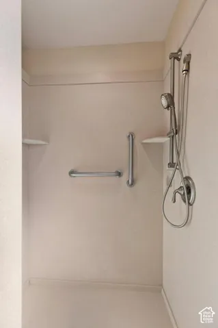 Walk-in shower with integrated corner shelving, brushed nickel fixtures, and safety grab bars