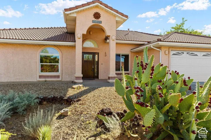 Stucco exterior with a tiled roof, arched entry, and a two-car garage