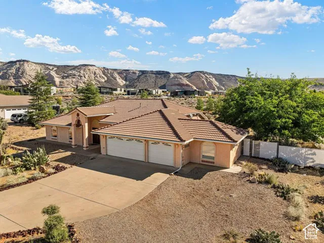 Terracotta tile roof with a prominent portico entry, two-car garage, and desert landscaping