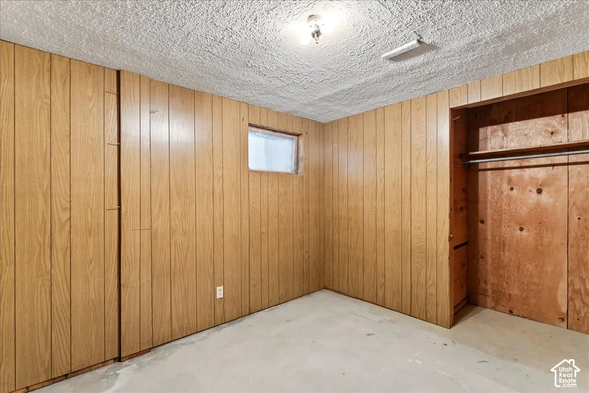Wood-panel walls with a built-in closet featuring a clothes rod and upper shelf
