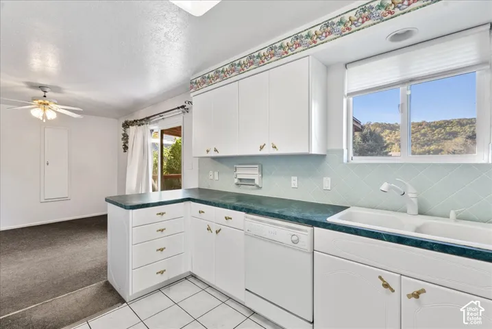 White cabinetry with brass hardware, double basin sink, light blue diamond-patterned backsplash, and durable countertops