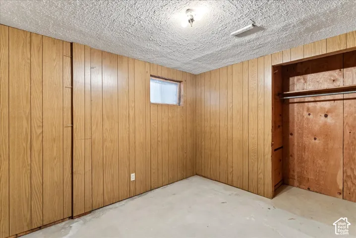 Wood-panel walls with a built-in closet featuring a clothes rod and upper shelf