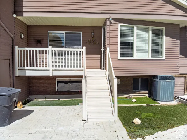Upper-level deck with white railing, exterior siding, and ground-level patio with artificial turf