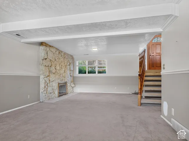 Stone-clad fireplace with hearth, carpeted flooring, and a window with horizontal blinds
