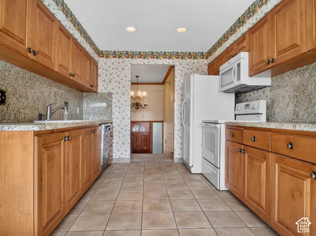 Full kitchen with wood-finish cabinetry, light-colored countertops, full-height backsplash, and tile flooring