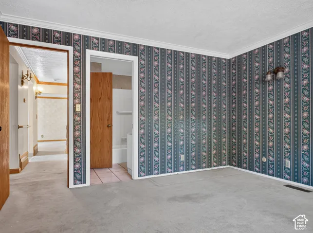 Carpeted room with floral wallpaper and crown molding