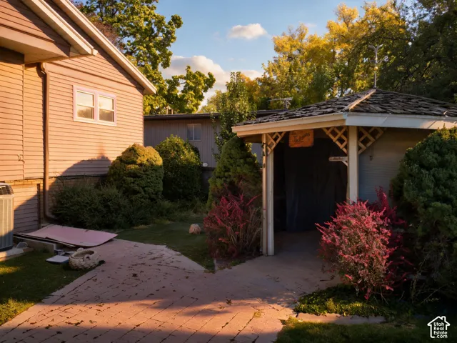 Siding exterior with multiple windows, complemented by a covered patio structure featuring a lattice accent and a shingle roof