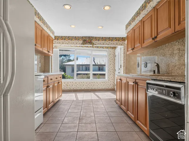 Kitchen featuring wood cabinetry, stone countertops, tile flooring, and recessed lighting