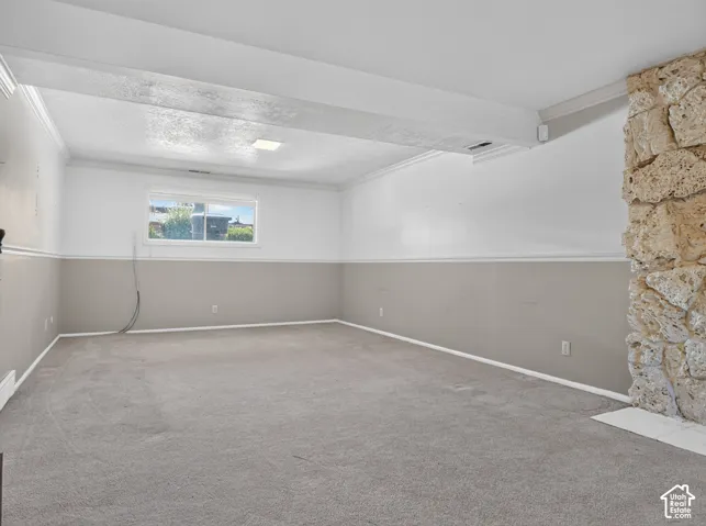 Expansive room with neutral carpeting, stone-clad fireplace, and a window