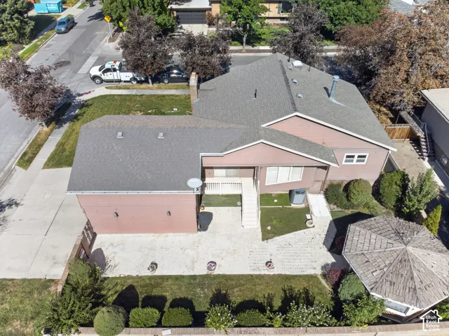 Expansive paved driveway and patio areas, mature landscaping, and multi-level exterior architecture