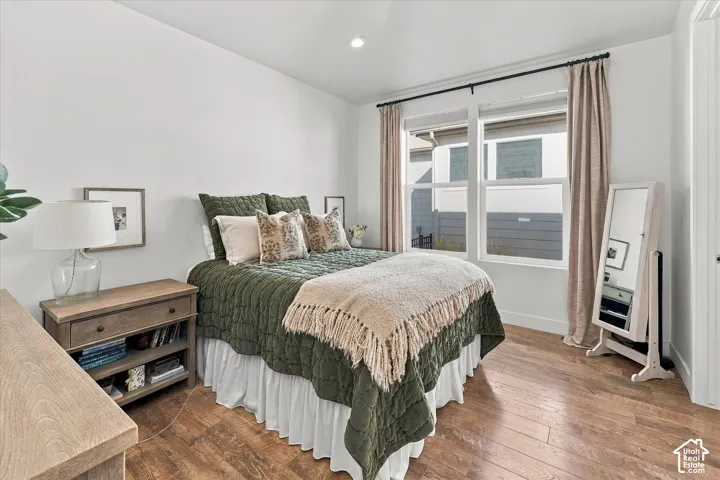 Recessed ceiling lighting, wood-finish flooring, and a large window with curtain rod