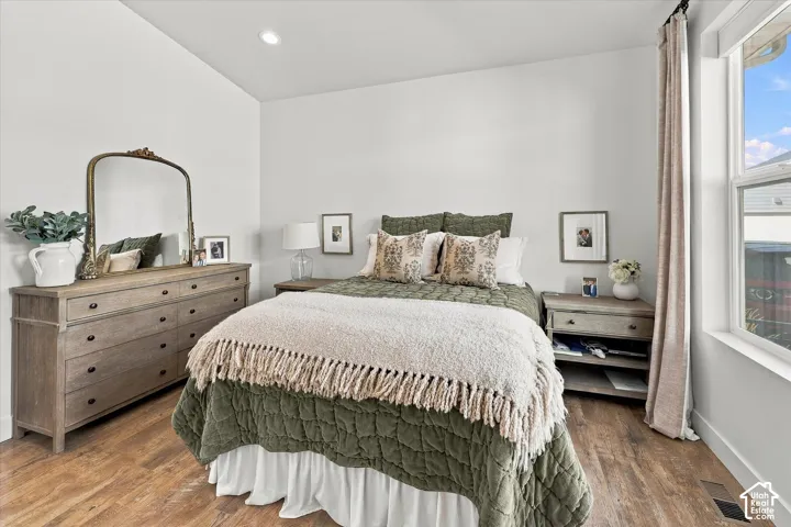 Recessed ceiling lighting, wood-finish flooring, and a large window with curtain rod