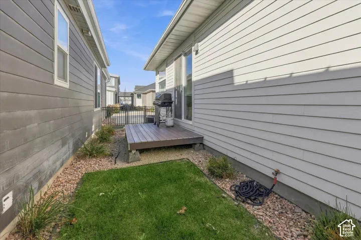 Side yard featuring a wood-finish deck, manicured lawn, and decorative gravel landscaping