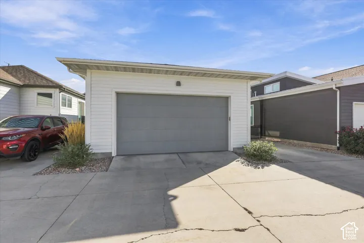Attached garage with a gray sectional door, white siding, and concrete driveway