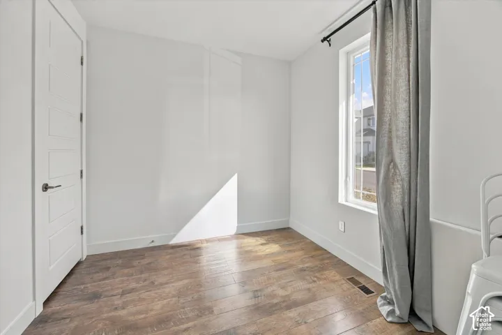 Wood-finish flooring, white walls, and a multi-pane window