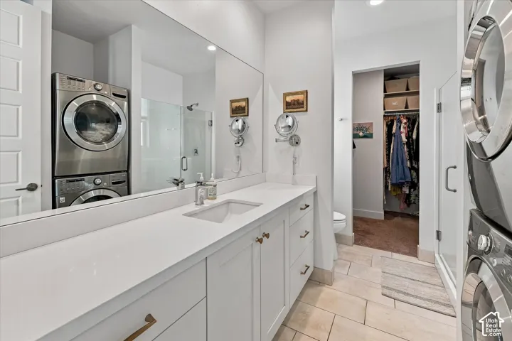 Vanity with a single undermount sink, a large mirror, and white cabinetry with brass hardware