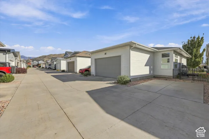 Attached two-car garage with a gray door, light-colored horizontal siding, and a paved driveway