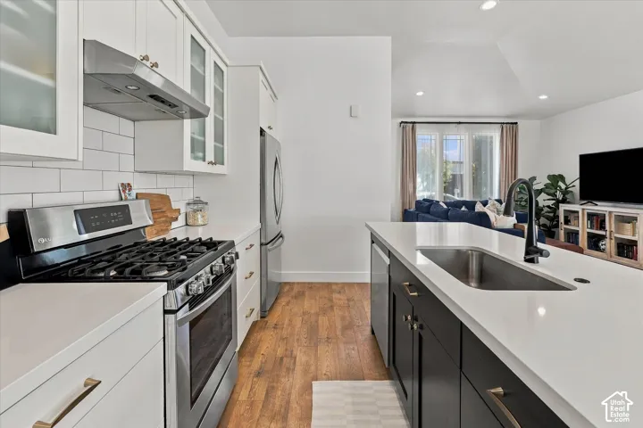 Modern kitchen featuring stainless steel appliances, white subway tile backsplash, white countertops, and wood-finish flooring