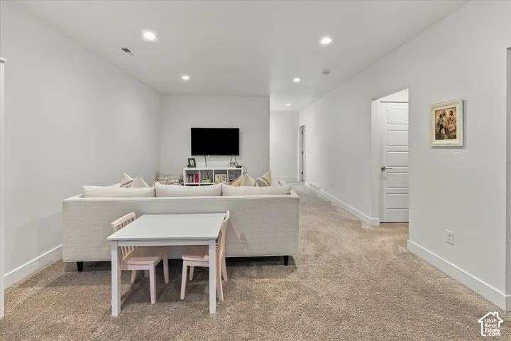 Carpeted living space with recessed lighting and neutral wall tones