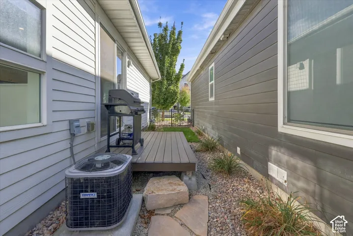 Exterior featuring composite siding, ground-level wood-look deck, decorative gravel landscaping, and a metal fence