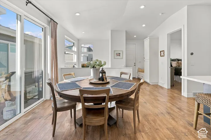 Wood-finish flooring throughout, white walls, recessed lighting, built-in bench seating, and multiple windows including a large sliding glass door