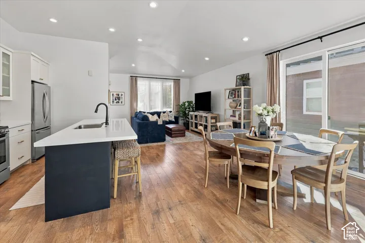 Open-concept living space featuring wood-finish flooring, recessed lighting, and a vaulted ceiling
