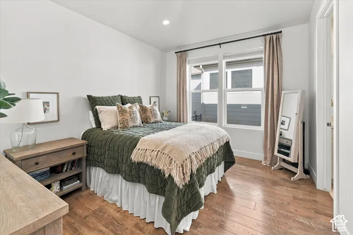 Recessed lighting, wood-finish flooring, white walls, and a window with white trim