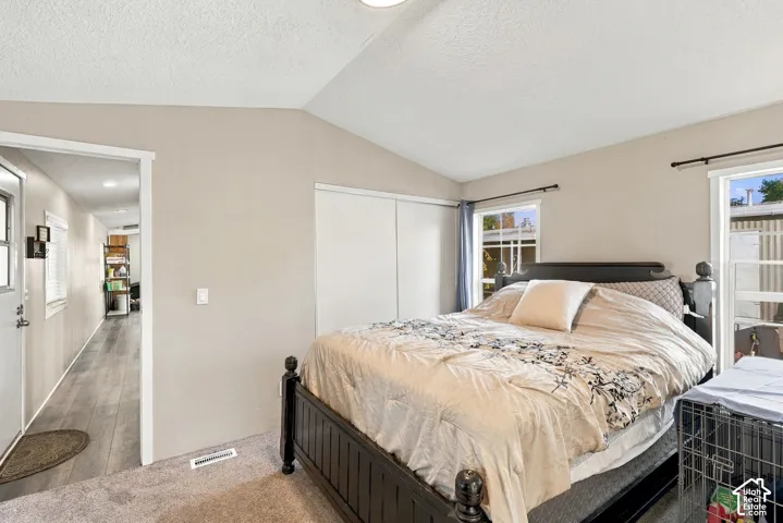 Neutral wall color, two windows, carpeted flooring, wood-finish flooring in hallway, built-in closet with sliding doors