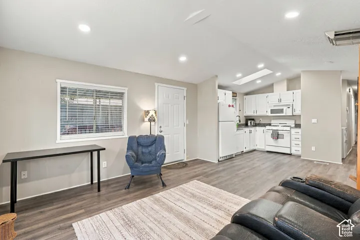 Open-concept living space featuring wood-finish flooring, recessed lighting, and a skylight