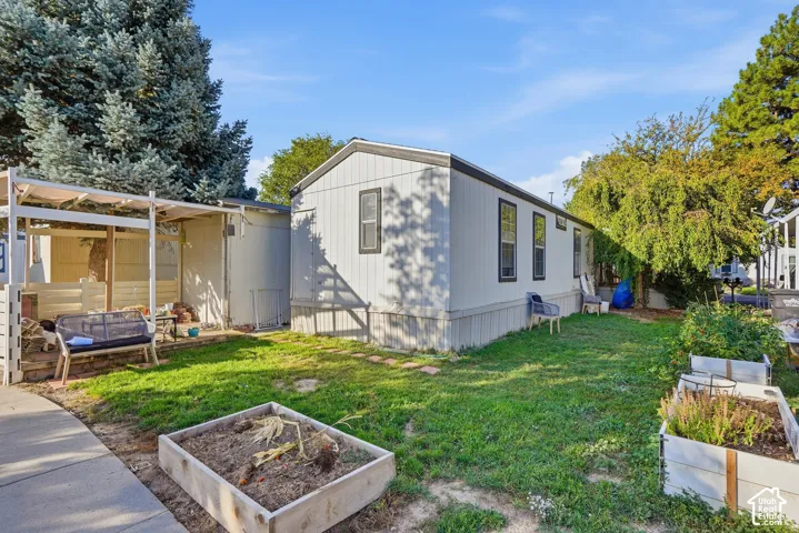 Manicured lawn, mature trees, white siding, dark-framed windows, and raised garden beds