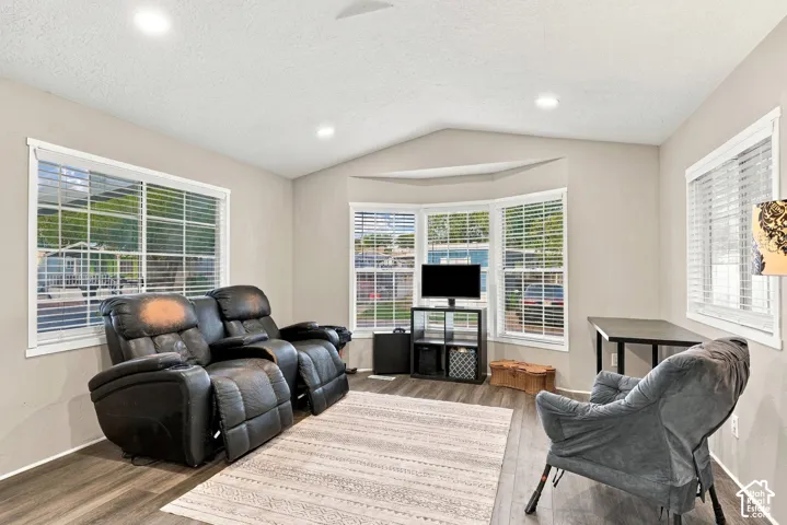 Wood-finish flooring, recessed lighting, vaulted ceiling, and multiple windows with blinds