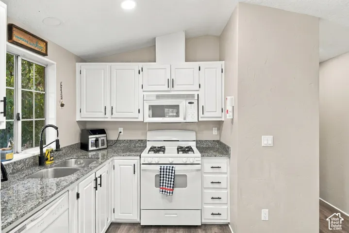 Kitchen featuring white cabinetry, a double basin stainless steel sink, a gas range, a built-in microwave, and stone-finish countertops