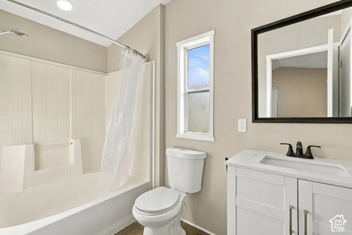 White vanity with a stone-finish countertop and matte black faucet, framed mirror, and a window providing natural illumination