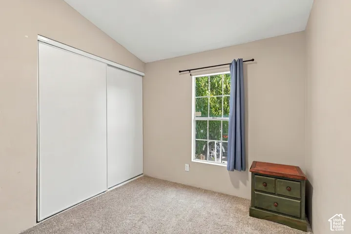 Sliding closet doors, wall-to-wall carpeting, single window, and sloped ceiling