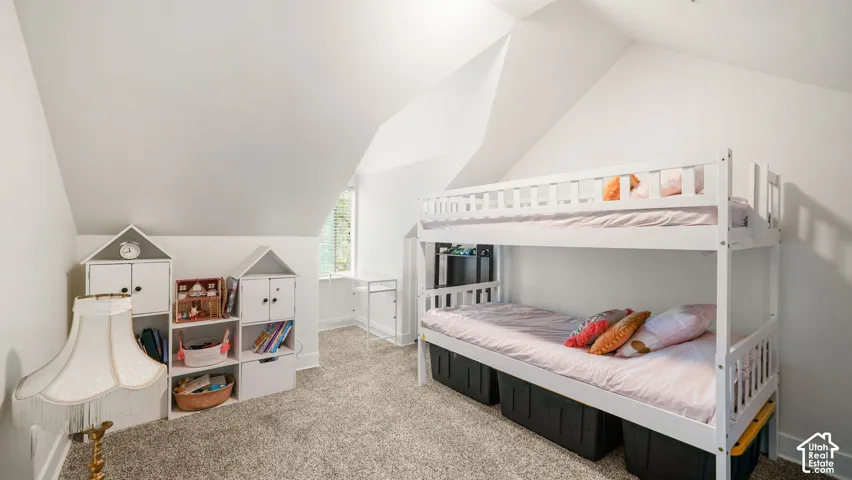 Sloped ceilings with recessed lighting, plush carpet flooring, and a window with natural light