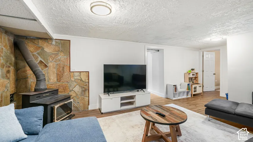 Wood-finish flooring, recessed lighting, and a stone-clad wall with a wood-burning stove