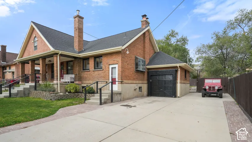 Brick exterior with a covered porch, attached single-car garage, and a concrete driveway