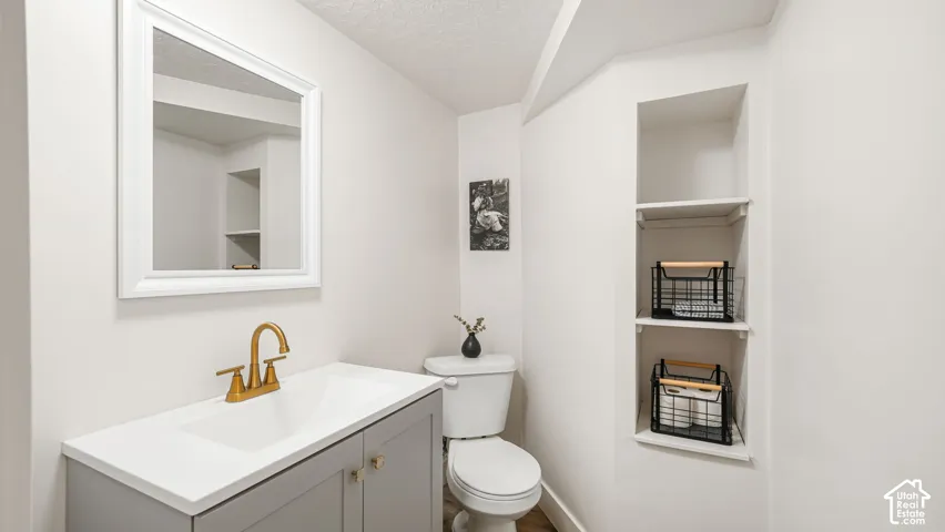 White vanity with a rectangular basin, gold-finish faucet, and coordinating hardware