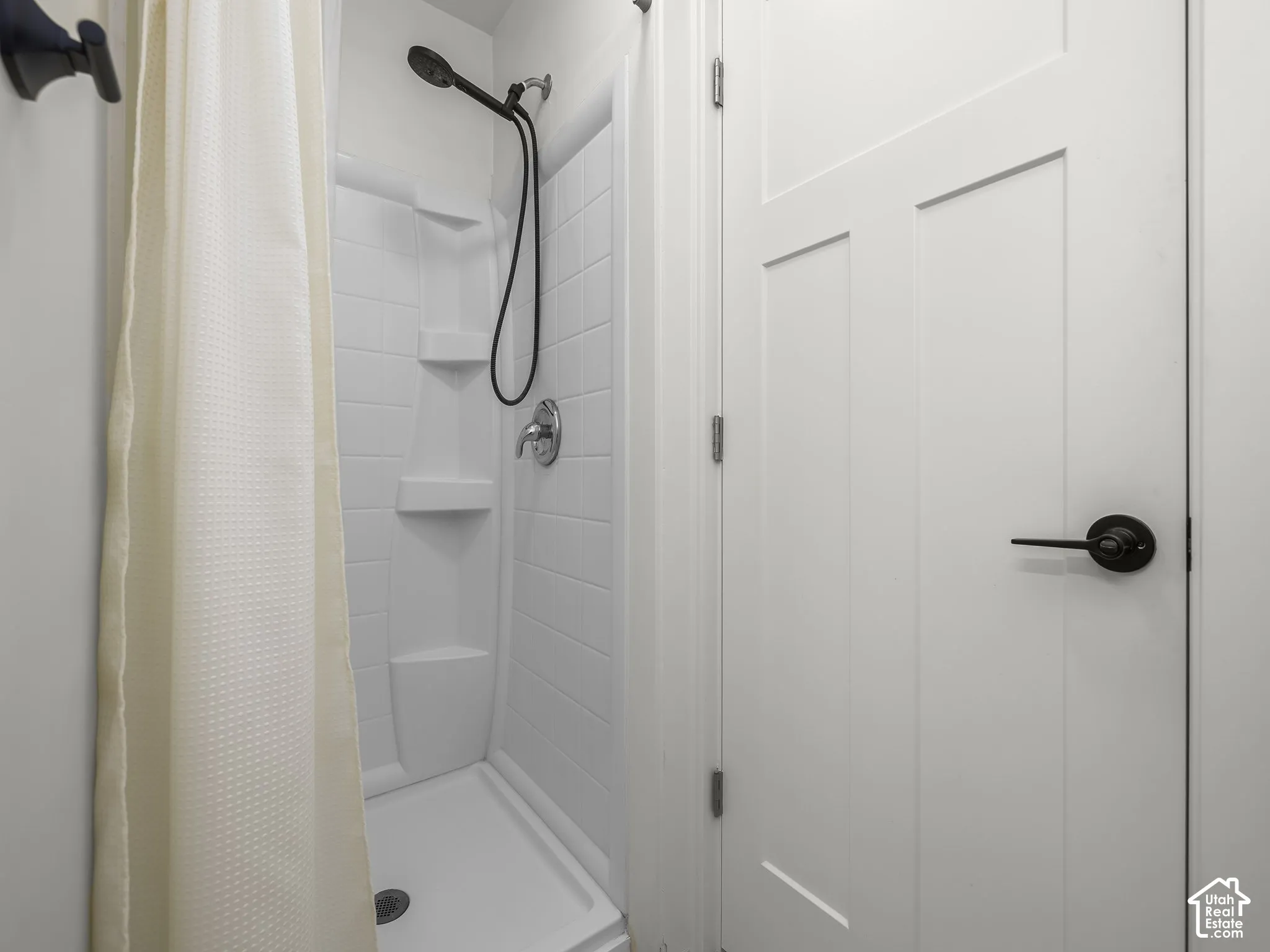 White fiberglass shower stall with integrated shelving and a chrome shower fixture